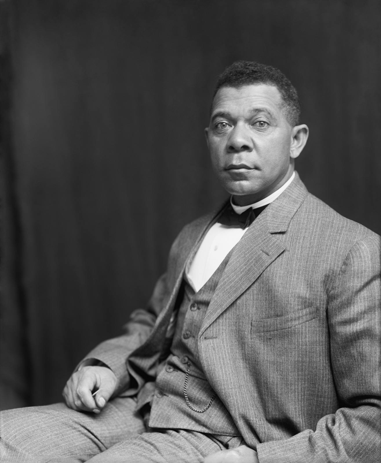 Black-and-white studio portrait of Booker T. Washington, seated, wearing a three-piece suit and bow tie, looking directly at the camera.